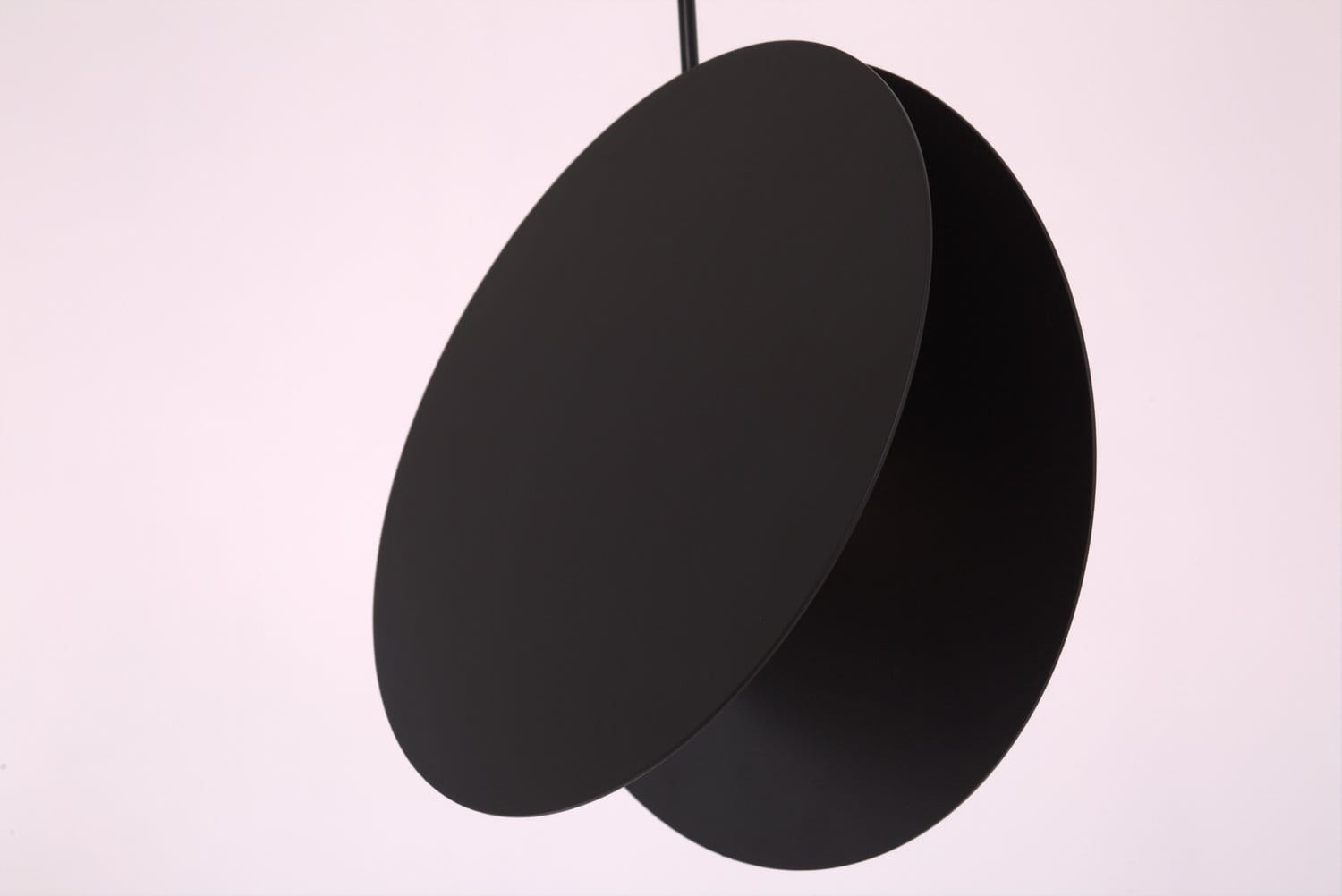 Lampa wisząca Pills 23 w kolorze czarnym, z jedną oprawą GU10. Prezentuje dwa okrągłe, matowe elementy o różnych średnicach, zawieszone na cienkim kablu. Tło w jasnym odcieniu podkreśla minimalistyczny design lampy.