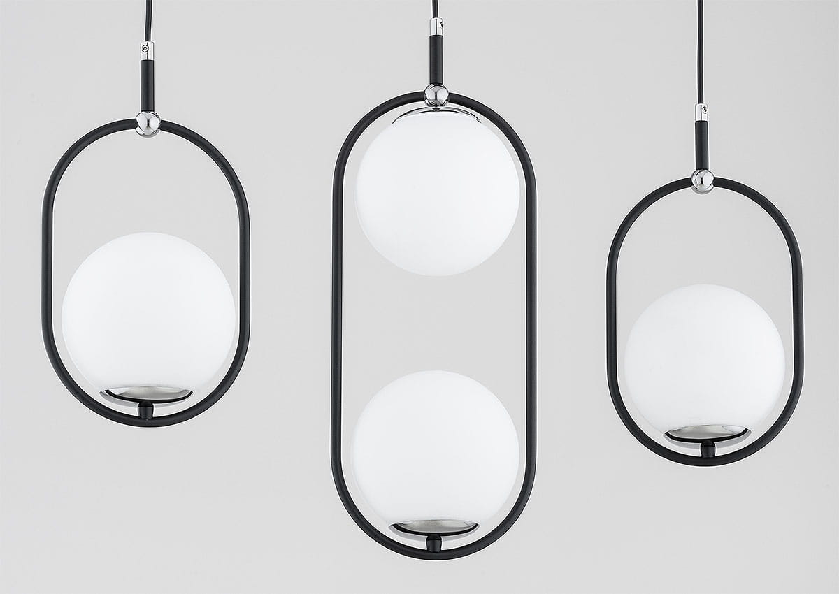 Lampa wisząca Amaro z czterema oprawami E14 w kolorze czarnym i chromowanym. Okrągłe, białe klosze zawieszone w metalowych ramkach, w różnych wysokościach. Produkt zawieszony na cienkich przewodach, na jasnym tle.