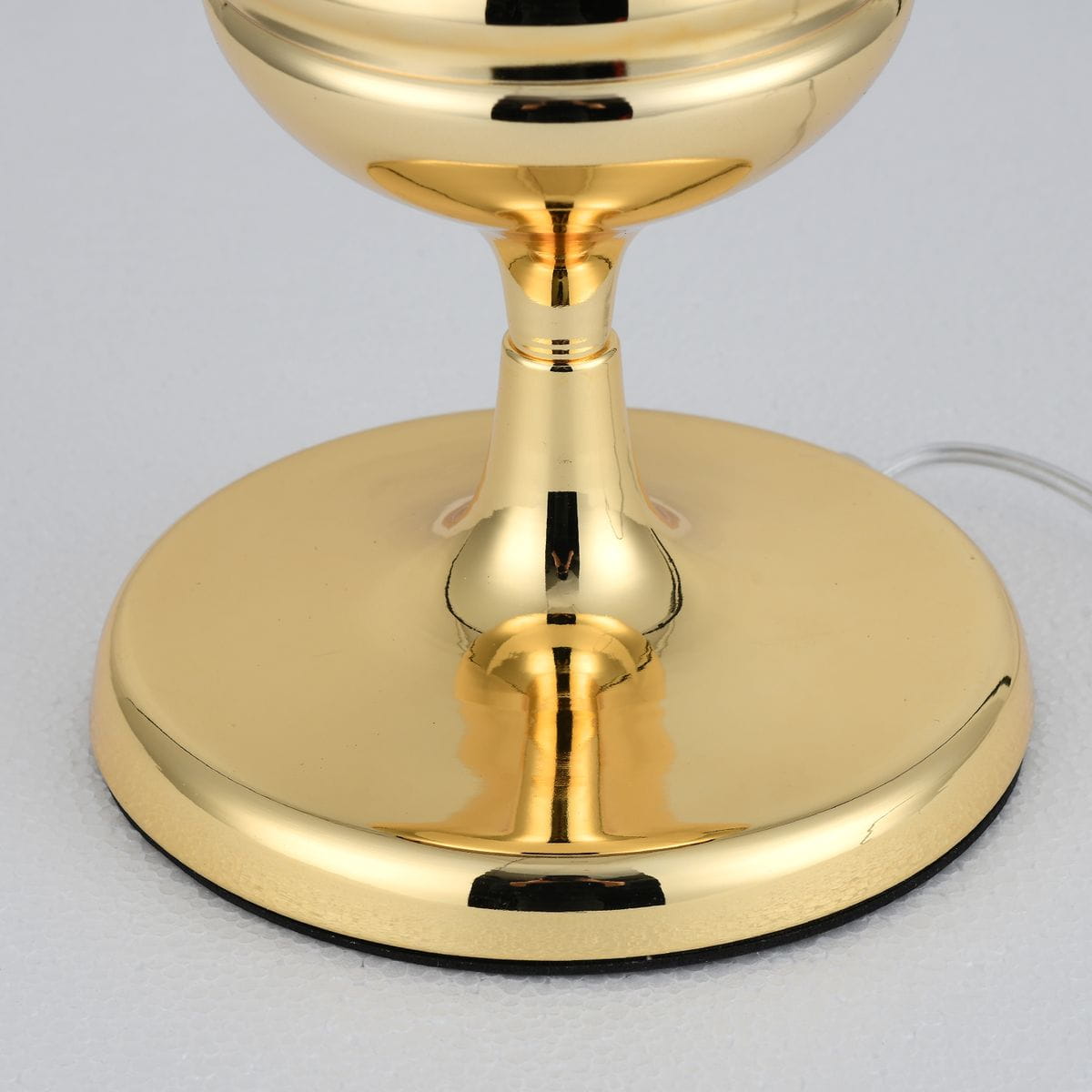 Lampa stołowa Queen H18 w kolorze złotym, z okrągłą podstawą i eleganckim trzonem. Widoczne detale to gładka, błyszcząca powierzchnia oraz cienki przewód zasilający. Ujęcie z bliska, skupione na dolnej części lampy.