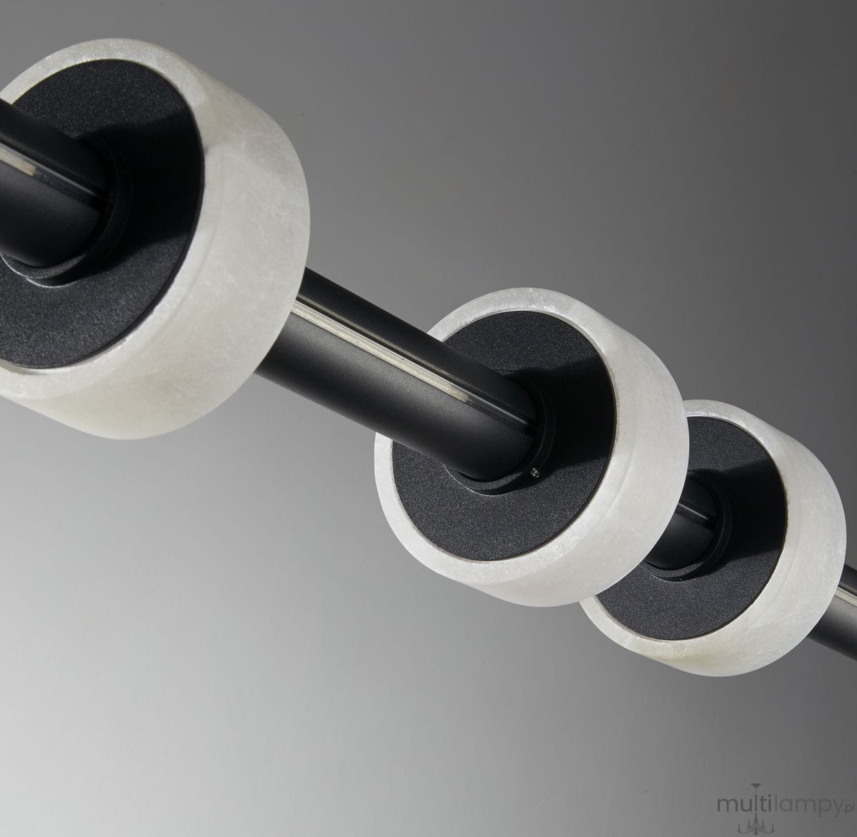 Lampa wisząca Ringo o czarnej konstrukcji z metalowym stelażem i trzema okrągłymi elementami w kolorze białym. Zbliżenie na detale mocowania i teksturę, ukazujące połączenie materiałów oraz minimalistyczny design.