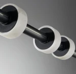 Lampa wisząca Ringo o czarnej konstrukcji z metalowym stelażem i trzema okrągłymi elementami w kolorze białym. Zbliżenie na detale mocowania i teksturę, ukazujące połączenie materiałów oraz minimalistyczny design.