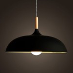 Lampa wisząca Saucer w kolorze czarnym z kloszem w kształcie półkuli, zawieszona na tekstylnym przewodzie. Górna część z drewna, a wewnątrz widoczna okrągła żarówka, emitująca ciepłe światło. Idealna do nowoczesnych wnętrz.