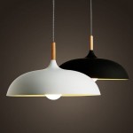 Lampa wisząca Saucer 1xE27 w kolorze czarnym, z okrągłym kloszem i drewnianym uchwytem. Zawieszona na metalowym przewodzie. Widoczna oprawka na żarówkę. Tło w odcieniach ciemnych.