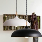 Lampa wisząca Saucer 1xE27 w kolorze białym, z metalowym kloszem w kształcie półkuli i drewnianym uchwytem. Zawieszona na czarnym kablu, obok czarnej wersji. Tło neutralne, z elementami dekoracyjnymi w tle.