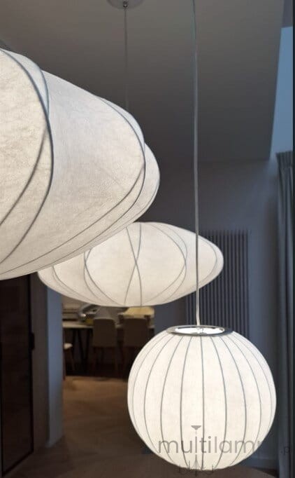 Lampa wisząca Silk D40 w kolorze białym z jednym źródłem światła E27. Posiada zaokrąglony kształt i teksturowaną powierzchnię z delikatnymi liniami. Wisi na cienkim przewodzie, w aranżacji wnętrza z widocznym tłem w neutralnych kolorach.