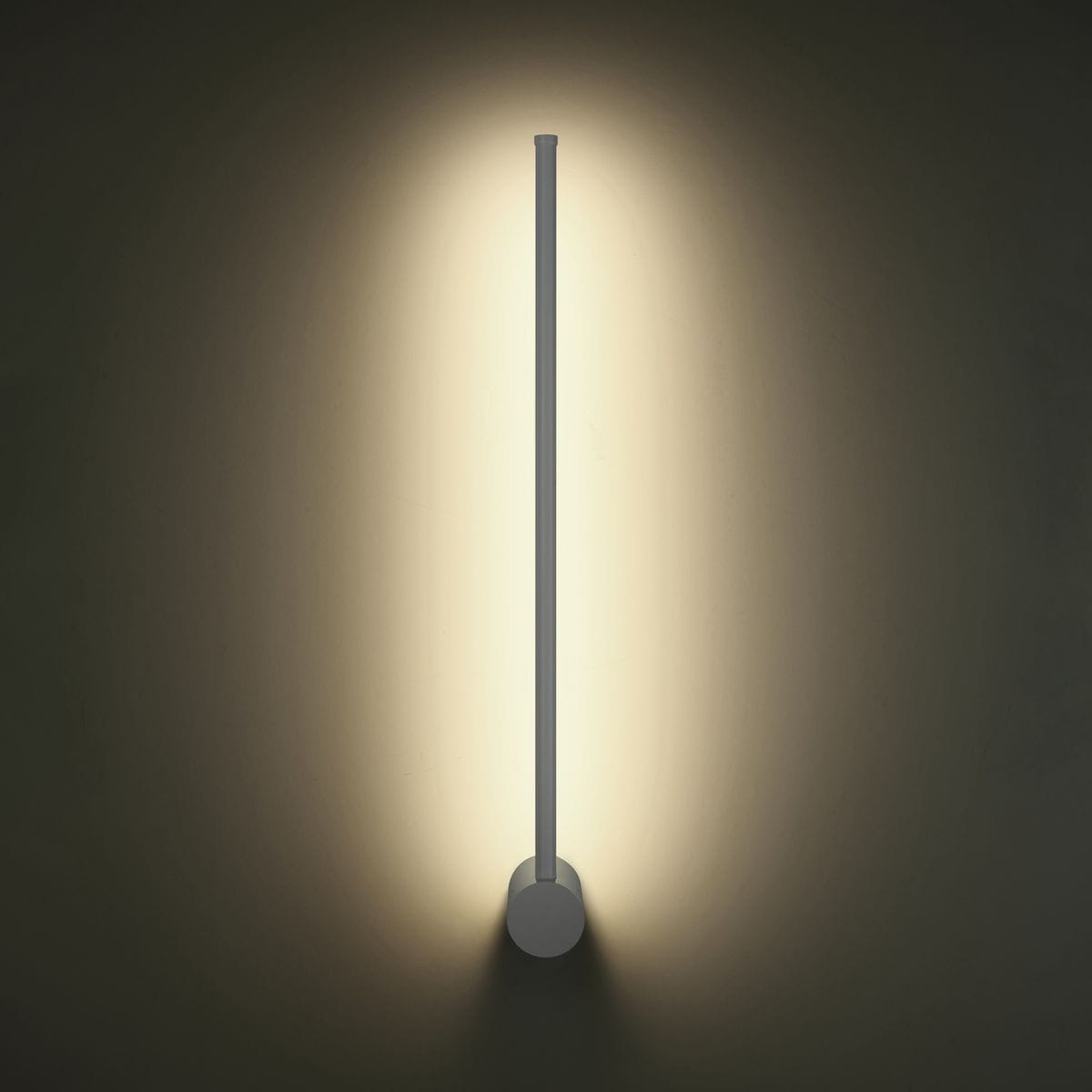 Biały kinkiet Sparo H60 z jednym źródłem LED o mocy 8W, zamontowany na ścianie. Prosta, cylindryczna forma z okrągłą podstawą, emitujący ciepłe światło, tworzy efektowne podświetlenie ściany.