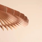 Lampa wisząca Nature Sun D69 o pojedynczym źródle światła E27, wykonana z metalowych, falistych elementów w odcieniach miedzi. Widoczny detal z bliska, ukazujący teksturę i kształt klosza w formie wachlarza na jasnym tle.