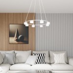 Lampa wisząca Starlit w kolorze białym, o okrągłej konstrukcji z ośmioma źródłami światła GX53. Zawieszona na trzech białych linkach w nowoczesnym wnętrzu z sofą i obrazem w tle.