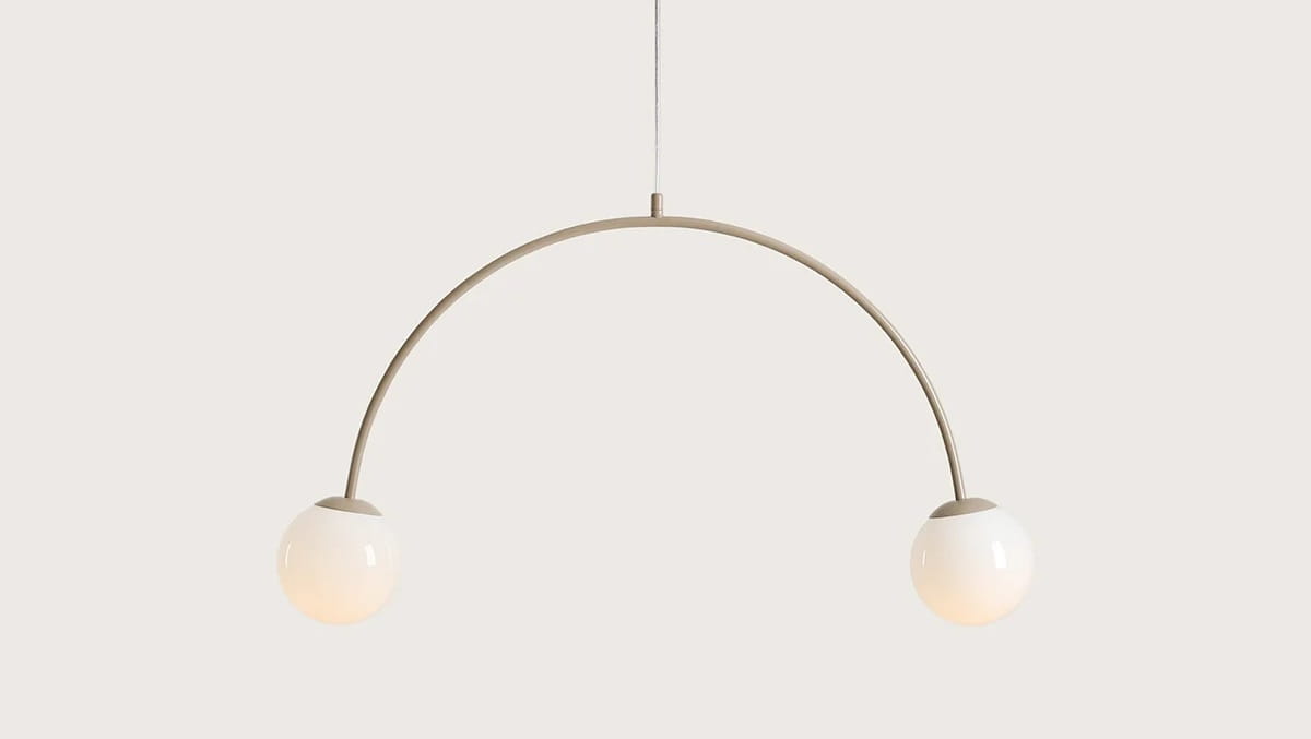 Lampa wisząca Una Beige z metalowym, łukowym ramieniem w kolorze beżowym, z dwiema kulistymi kloszami w odcieniu białym. Ujęcie frontalne, zawieszona na cienkim przewodzie, idealna do nowoczesnych wnętrz.
