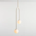 Lampa wisząca Nave w kolorze kremowym z dwoma okrągłymi kloszami. Klosze zawieszone na długim, łukowatym ramieniu, emitujące ciepłe światło. Prosta forma, idealna do nowoczesnych wnętrz, umieszczona na jasnym tle.
