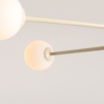 Kremowa lampa sufitowa Pinne z czterema oprawami E14, złożona z okrągłych kloszy w matowym wykończeniu. Klosze zawieszone na cienkich, prostych ramionach, widok z dołu. Idealna do nowoczesnych wnętrz.