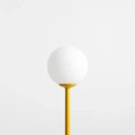 Lampa stołowa Pinne 1xE14 w kolorze żółtym, z białą, okrągłą kloszem na smukłej podstawie. Produkt prezentowany z boku na jednolitym tle, podkreślający jego prostą formę i nowoczesny design.