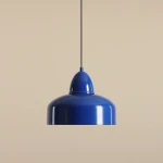 Lampa wisząca Como Cobalt 1-punktowa w intensywnym błękicie, metalowa, o zaokrąglonym kształcie z gładką, błyszczącą powierzchnią. Zawieszona na czarnym przewodzie, z widoczną dekoracyjną górą, na neutralnym, jasnym tle.