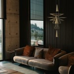 Lampa wisząca Susso D40 w kolorze złotym, z dwoma oprawami GU10, zawieszona w nowoczesnym wnętrzu. Kształt asymetryczny, z metalowymi elementami, umieszczona nad sofą z poduszkami w odcieniach brązu. Tło z oknami i betonową ścianą.