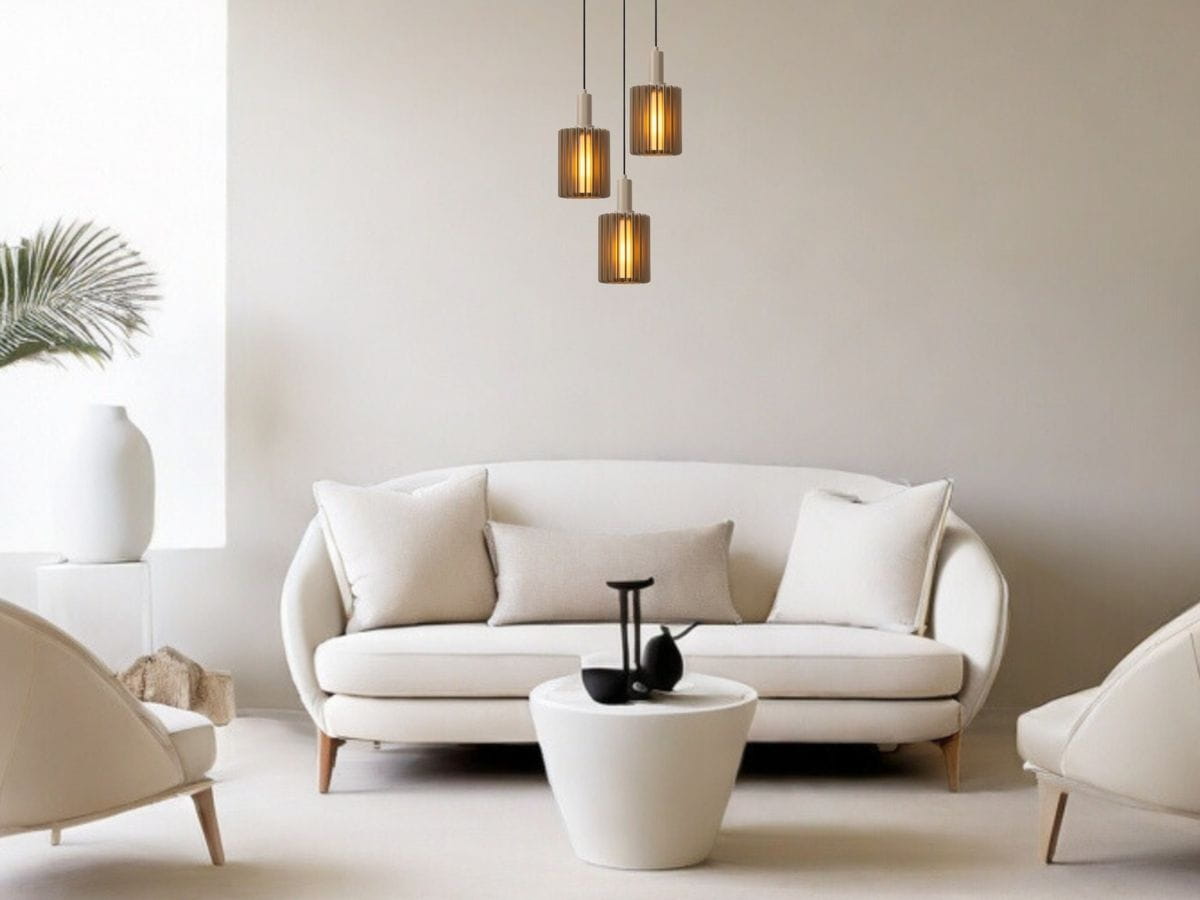Lambre lampa wisząca 3xE27 w szarym kolorze, z trzema cylindrycznymi kloszami w odcieniu złotym, zawieszona nad białą sofą w nowoczesnym wnętrzu. Tło jasne, z minimalistycznymi meblami i roślinnością.