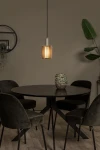 Lambres lampa wisząca 1xE27 w kolorze szarym, z cylindrycznym kloszem, zawieszona na czarnym przewodzie. Lampa znajduje się nad okrągłym, ciemnym stołem w otoczeniu zielonych krzeseł i dekoracyjnej donicy. Tło w neutralnym odcieniu.