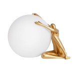 Lampa stołowa Woman w kolorze złotym, przedstawiająca stylizowaną postać trzymającą białą, okrągłą kulę. Produkt w pozycji siedzącej, z lekko zgiętymi nogami, podkreślający elegancki design. Idealna do nowoczesnych wnętrz.