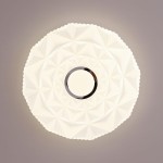 Plafon Kelmi D27 w kolorze białym i srebrnym, z LED 12W, 4000K. Okrągły kształt z dekoracyjną, teksturowaną powierzchnią. Widoczny centralny okrąg z metalicznym wykończeniem. Ujęcie z góry, na jasnym tle.