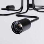 Czarna lampa sufitowa Vector z sześcioma gniazdami E27. Widok z bliska na uchwyt żarówki, z metalowym wykończeniem i widocznymi stykami. Przewody w formie zakrzywionej, minimalistyczny design. Tło białe, prosty układ.