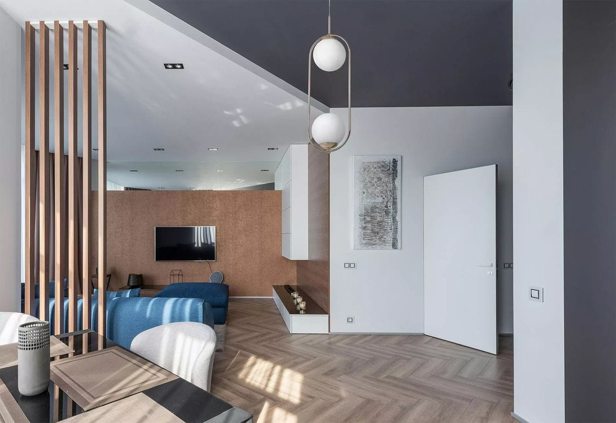 Lampa wisząca Ritus 2xE14 w kolorze złotym i białym, z dwiema okrągłymi kloszami, zawieszona w nowoczesnym wnętrzu. Widoczna w aranżacji z elementami drewnianymi i sofą. Ujęcie z góry, ukazujące detal i kształt lampy.