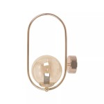 Złoty kinkiet Sven z bursztynową, szklaną kulą. Lekka, metalowa konstrukcja w formie elipsy, montowana na ścianie. Widoczny gwint E14 wewnątrz kuli. Prosta, nowoczesna forma, idealna do aranżacji wnętrz.