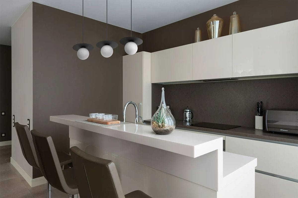 Lampa wisząca Robin D18 w kolorze czarnym i białym z jednym źródłem światła G9, zawieszona nad białym blatem kuchennym. W tle widoczna nowoczesna kuchnia z szafkami w jasnych kolorach oraz dodatkami dekoracyjnymi.