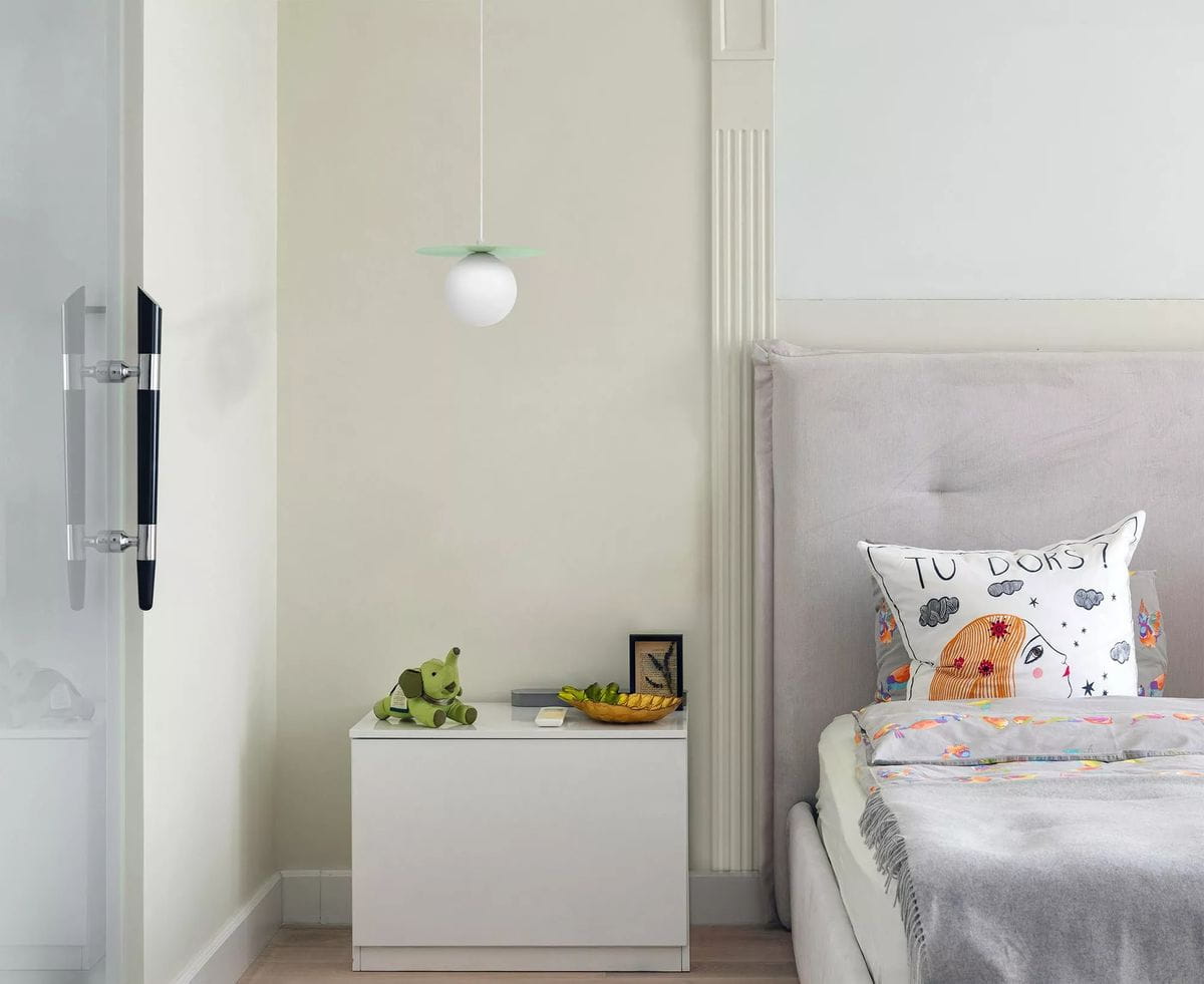 Lampa wisząca Robin D18 w kolorze miętowym i białym, z okrągłym kloszem zawieszonym na cienkim przewodzie. Widoczna w nowoczesnej sypialni nad białym stolikiem nocnym, obok poduszki z nadrukiem.
