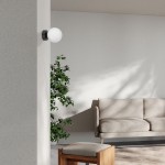 Lampa sufitowa Inez 1xE14 w kolorze czarnym i białym, zamontowana na ścianie. Okrągła, biała kula świetlna kontrastuje z czarnym uchwytem. W tle widać roślinę oraz sofę w jasnym kolorze na tle szarej ściany.