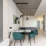 Lampa wisząca Fermi w kolorze czarnym i grafitowym z trzema kloszami z metalowymi elementami. Zawieszona na długich linkach nad szklanym stołem w nowoczesnej aranżacji jadalni, z zielonymi krzesłami i jasnym tłem.