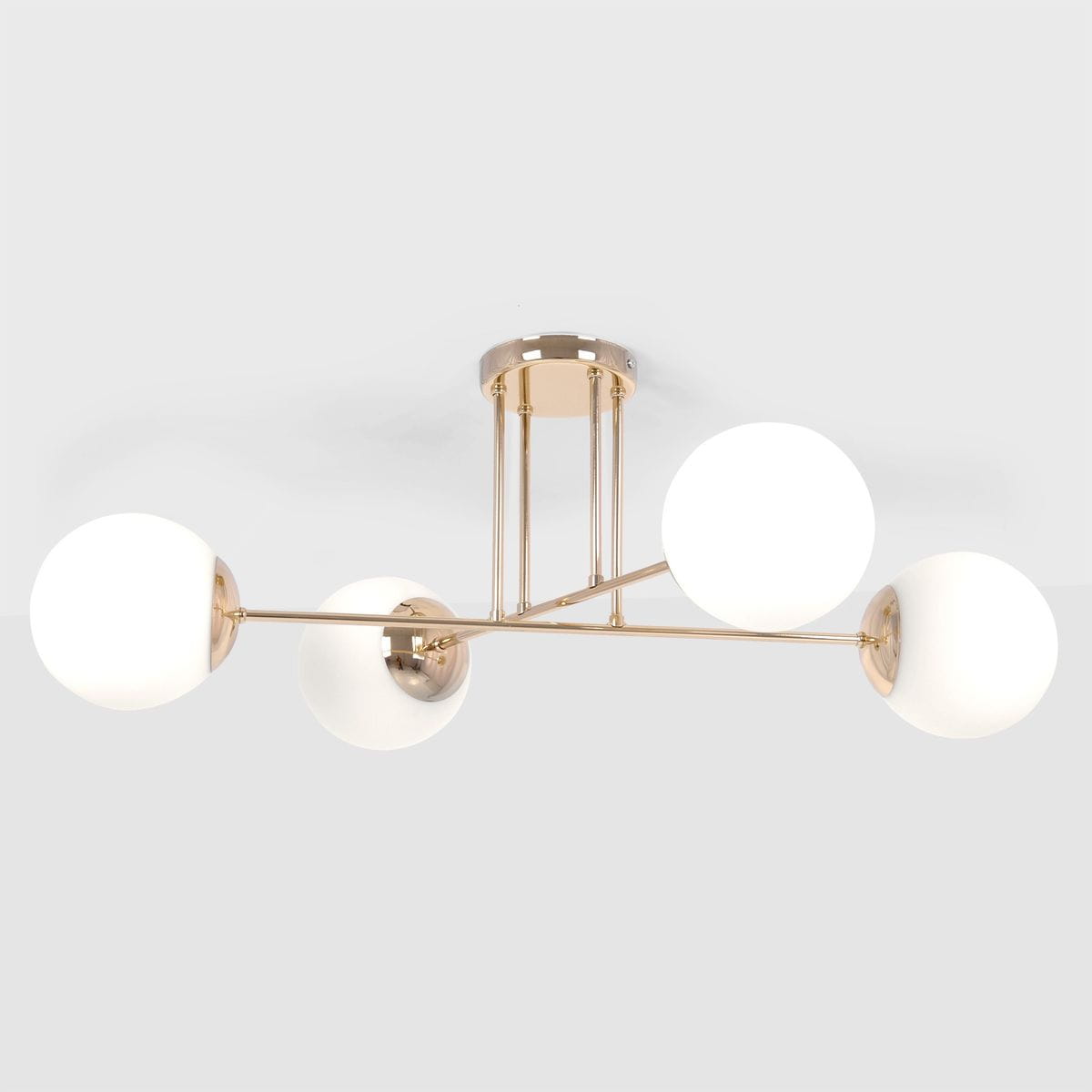 Lampa sufitowa Lumia z czterema oprawami E27, w kolorze złotym i białym. Okrągłe klosze z matowego szkła umieszczone na metalowych ramionach. Produkt zamontowany na okrągłej podstawie. Ujęcie frontalne.