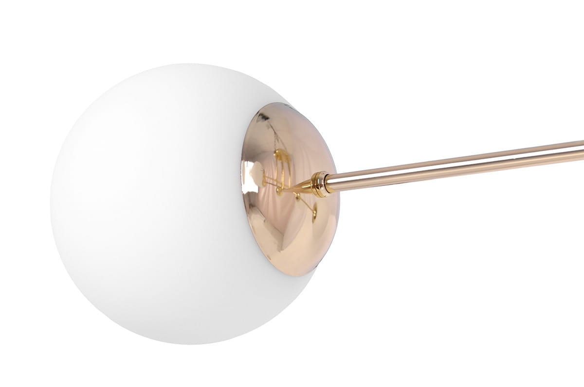 Lampa sufitowa Lumia w kolorze złotym i białym, z sześcioma gniazdami E27. Okrągła, matowa biała kula z metalowym złotym detalem. Ujęcie z boku, ukazujące połączenie kuli z prostymi liniami. Idealna do nowoczesnych wnętrz.