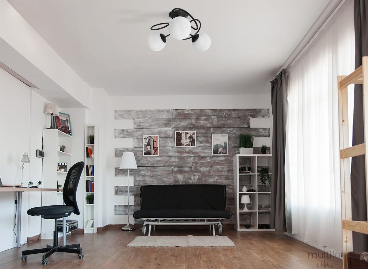 Lampa sufitowa Nela w kolorze czarnym i białym, z trzema oprawami na żarówki E14. Ujęcie z dołu, ukazuje elegancki, nowoczesny design. Produkt zamontowany na suficie, w jasnym wnętrzu z drewnianą ścianą i minimalistycznym wyposażeniem.