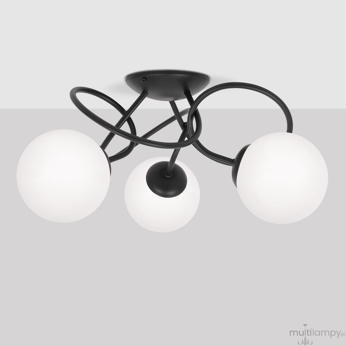 Lampa sufitowa Nela z trzema oprawami E14, w kolorze czarnym i białym. Posiada okrągłe, matowe klosze z białego szkła, zamontowane na czarnych, zakrzywionych ramionach. Ujęcie z dołu, pokazujące detale konstrukcji i rozmieszczenie kloszy.