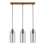 Lampa wisząca Naster z trzema dymionymi kloszami, zawieszona na drewnianym stelażu. Klosze mają cylindryczny kształt, wykonane z przezroczystego szkła, z drewnianymi elementami na górze. Całość zawieszona na czarnych kablach.