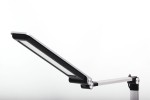 Srebrna lampka biurkowa Rico z jedną diodą LED (10W), z regulowanym ramieniem. Ujęcie z boku pokazuje panel świetlny z czarną ramką oraz metalowe elementy mocujące. Tło białe, co podkreśla nowoczesny design lampki.