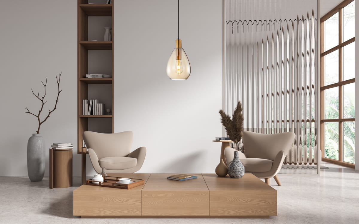Lampa wisząca Zulo z oprawą w czarnym kolorze, z bursztynowym kloszem w kształcie kropli, zawieszona na czarnym przewodzie. Widoczna w nowoczesnym wnętrzu z beżowymi fotelami i drewnianymi meblami.