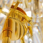 Luxe żyrandol w złotym kolorze, z widocznymi elementami metalowymi i dekoracyjnymi detalami. Ujęcie z bliska, ukazujące mocowanie oraz teksturę powierzchni. Produkt przeznaczony do oprawy 69xE14.