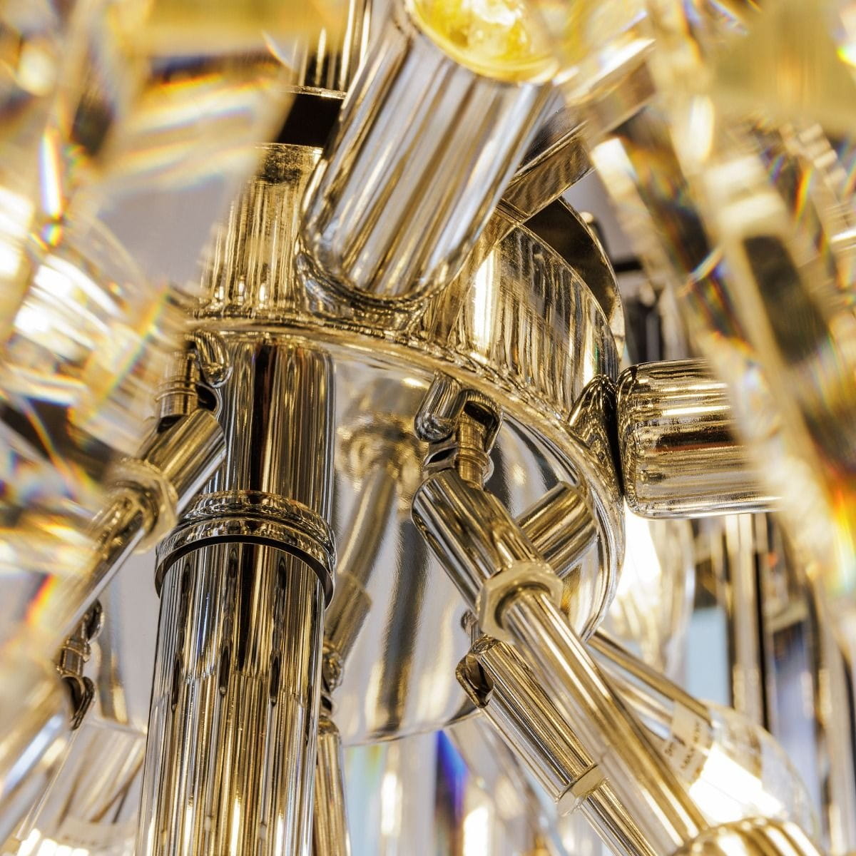 Luxe żyrandol w chromowanej obudowie, z widocznymi elementami szklanymi i żarówkami E14. Ujęcie z dołu, ukazujące szczegóły konstrukcji oraz refleksy świetlne. Złożony, elegancki design, idealny do nowoczesnych wnętrz.