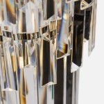 Luxe żyrandol w chromowanej oprawie, z wiszącymi kryształowymi elementami w formie prostokątów i trójkątów. Zdjęcie ukazuje detal refleksów świetlnych na kryształach oraz metalowe wykończenie.