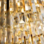 Złoty żyrandol Luxe z 40 miejscami na żarówki E14, z widocznymi szklanymi elementami w kształcie prostokątnych pryzmatów, które odbijają światło, tworząc efektowne refleksy. Ujęcie z bliska, ukazujące detale struktury i faktury.