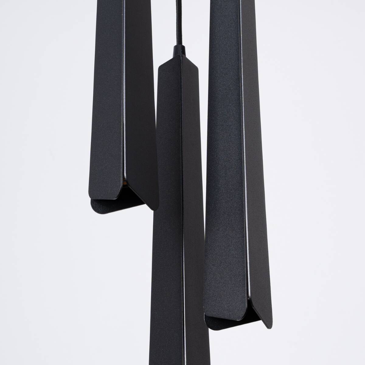 Lampa wisząca Prysm 3P w kolorze czarnym z trzema źródłami światła G9. Składa się z trzech smukłych, prostopadłościennych elementów z matowego materiału, zawieszonych na czarnym kablu. Tło białe, co podkreśla wygląd lampy.