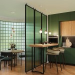 Lampa wisząca Pekka 3P z trzema źródłami światła G9, w drewnianych detalach, zawieszona nad drewnianym blatem w kuchni. Oświetlenie w minimalistycznym stylu, z okrągłymi kloszami. Tło z zielonymi akcentami i przeszklonymi ściankami.