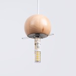 Lampa wisząca Pekka z drewnianą kulą w kolorze naturalnego drewna, z oprawką G9. Zawieszona na białym przewodzie, z widoczną żarówką LED. Kula ma gładką powierzchnię, a metalowa podstawka zabezpiecza żarówkę. Tło proste, szare.