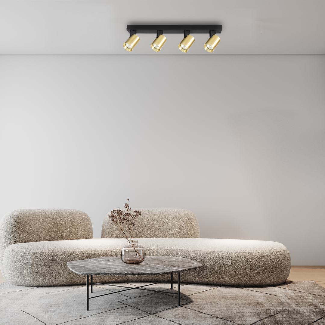 Lampa sufitowa Volf w kolorze czarnym i złotym, z czterema ruchomymi reflektorami GU10. Zamontowana na suficie, w nowoczesnym wnętrzu z kanapą i stołem. Widoczne detale reflektorów oraz minimalistyczny design.
