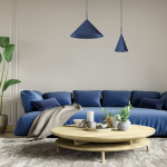 Granatowa lampa wisząca Capital D46 z jedną oprawą GX53, o stożkowym kształcie, zawieszona nad okrągłym, drewnianym stołem w aranżacji z niebieską sofą i roślinnością w tle. Dodatkowo widoczne dekoracje na stole.