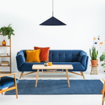 Granatowa lampa wisząca Capital D60 z oprawą na żarówkę GX53, o stożkowym kształcie, zawieszona nad drewnianym stołem w nowoczesnym wnętrzu. W tle niebieska sofa, rośliny oraz dekoracyjna ścianka.