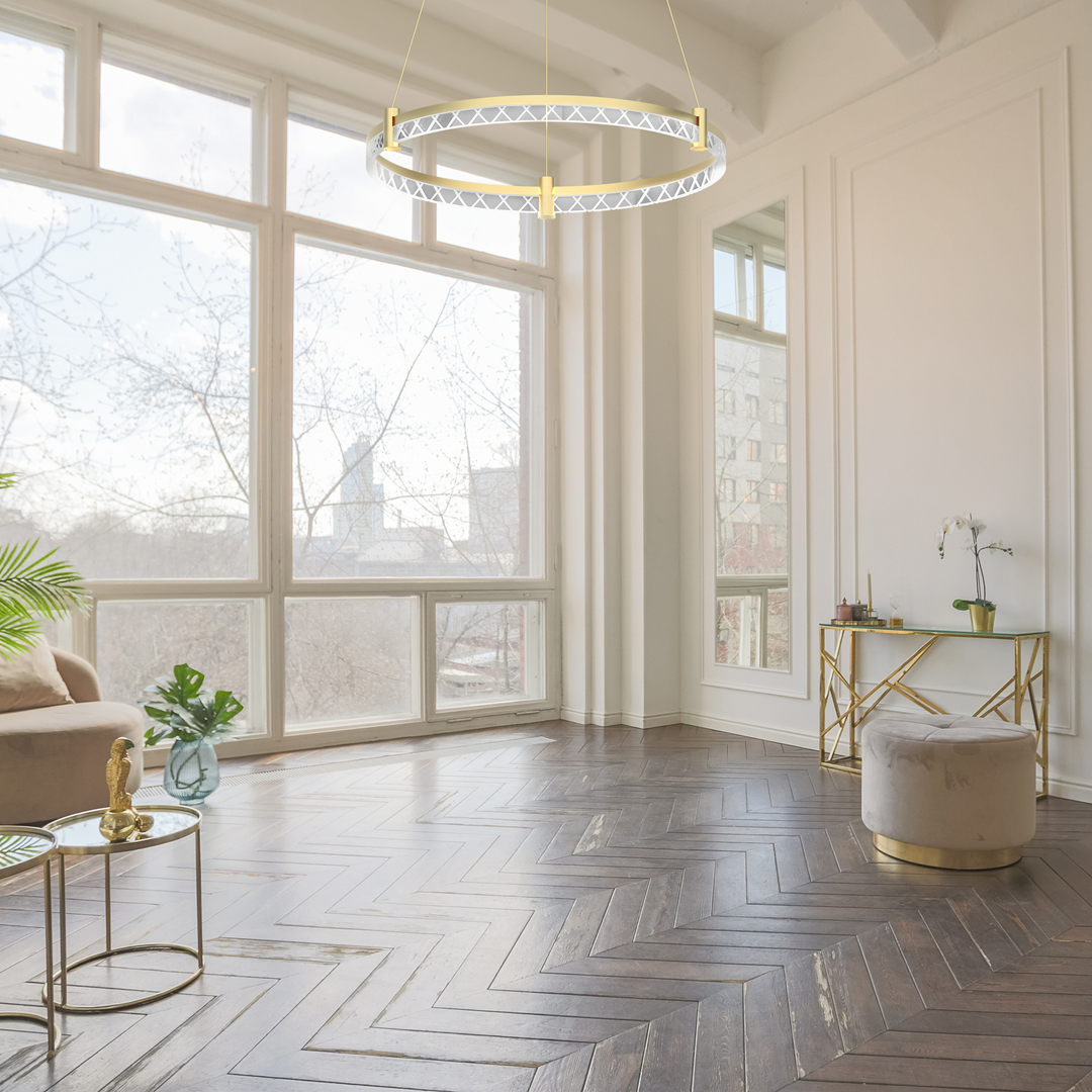Lampa wisząca Elegance D60 w kolorze złotym z jedną żarówką LED o mocy 36W, zawieszona w jasnym wnętrzu z dużymi oknami. Okrągły klosz z delikatnym wzorem, umieszczony nad eleganckim stolikiem kawowym i sofą.