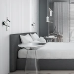 Kinkiet Twist w kolorze czarnym z jedną diodą LED o mocy 12W, zamontowany na ścianie po obu stronach łóżka. Stylowy, wygięty kształt oraz minimalistyczny design, idealny do nowoczesnych wnętrz. Tło jasne, z elementami drewnianymi i tekstylnymi.