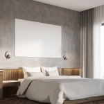 Kinkiet Lucero 1xLED/13W w kolorze czarnym, zamontowany na ścianie obok łóżka. Okrągła podstawa z metalowym wykończeniem, w tle szare ściany i drewniane elementy. Widać białą pościel na łóżku oraz jasne zasłony.
