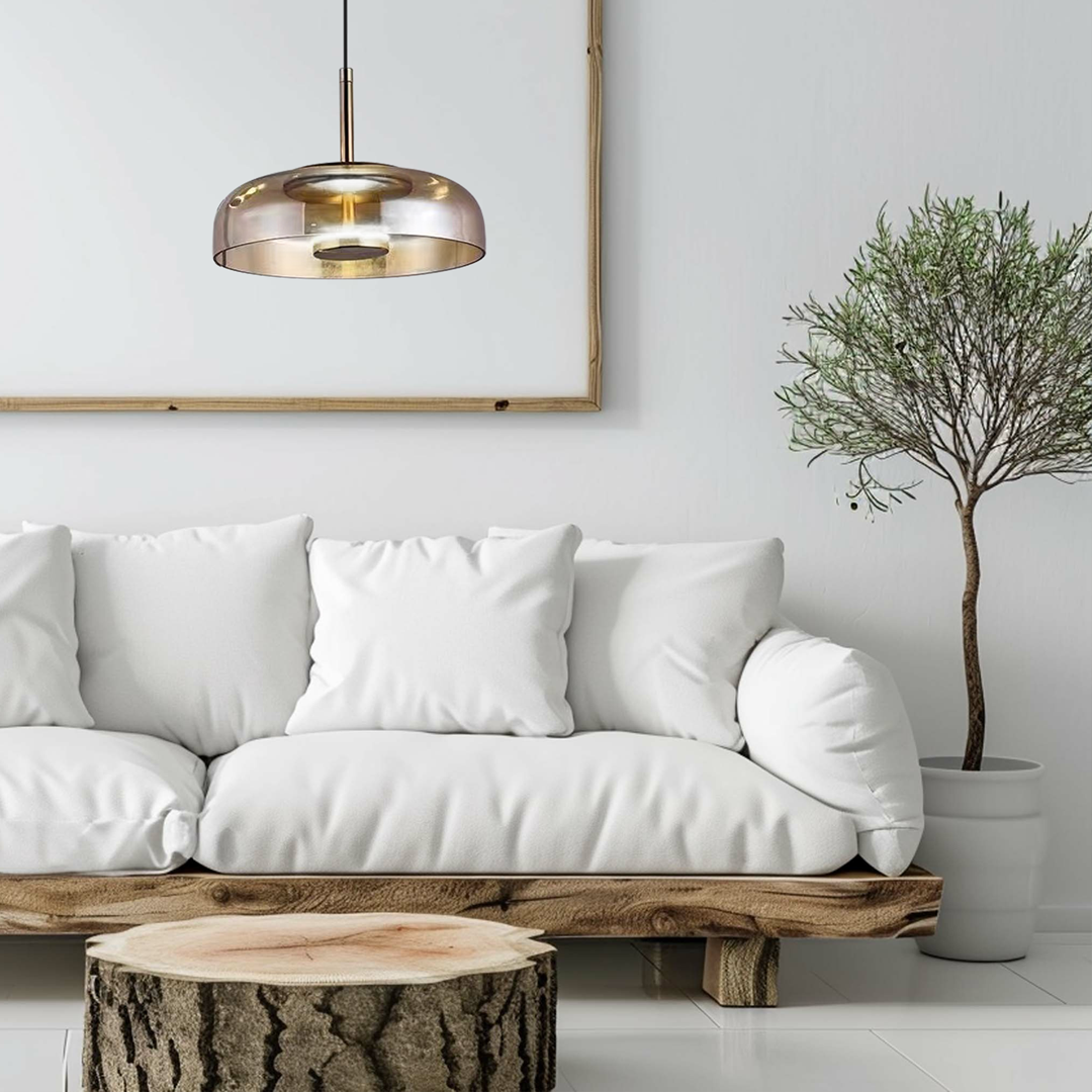 Lampa wisząca Vetro 1xLED/6W w kolorze czarnym z bursztynowym kloszem, o okrągłym kształcie, zawieszona nad białą sofą w stylowym wnętrzu. Widoczna drewniana ława i roślina w doniczce w tle.